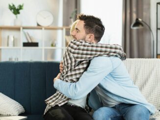 Same sex couple sitting on couch in strong hugs